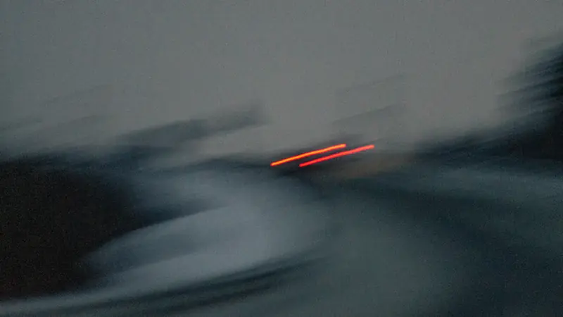 Hızın ve hareketin izini taşıyan, bulanık far ışıklarıyla soyut gece görüntüsü