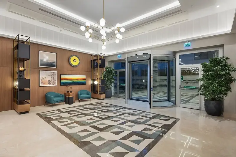 DoubleTree by Hilton Afyonkarahisar giriş holü: geometrik mermer kakma zemin, küre avize, ahşap kaplı duvar ve döner kapı
