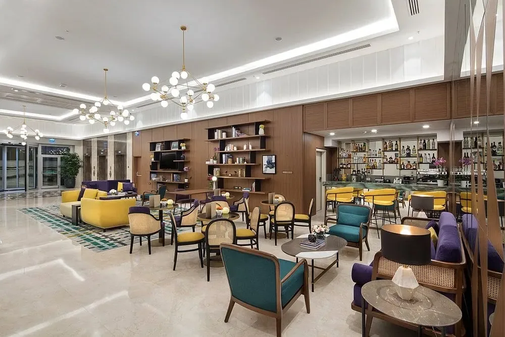 DoubleTree by Hilton Afyonkarahisar lobi barı: sarı, mor ve yeşil koltuklar, aydınlatmalı raflar ve küre avizeler